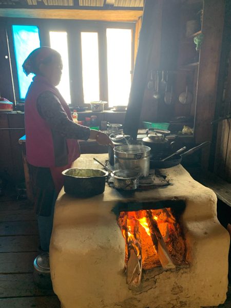 Local Tamang woman cooking with traditional firewood stove